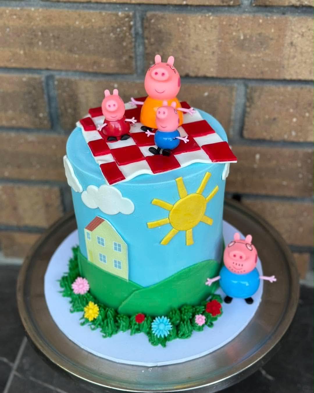 Peppa Pig birthday cake with fondant Peppa Pig family figurines, checkered picnic blanket and garden scene